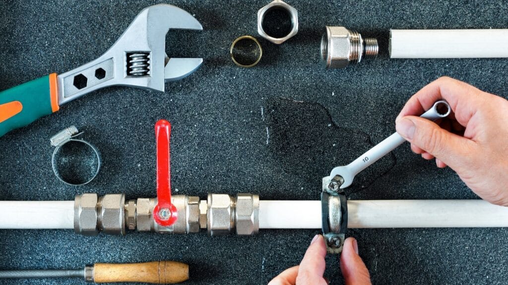 Plumber repairing a pipe valve with an adjustable wrench in Miami
