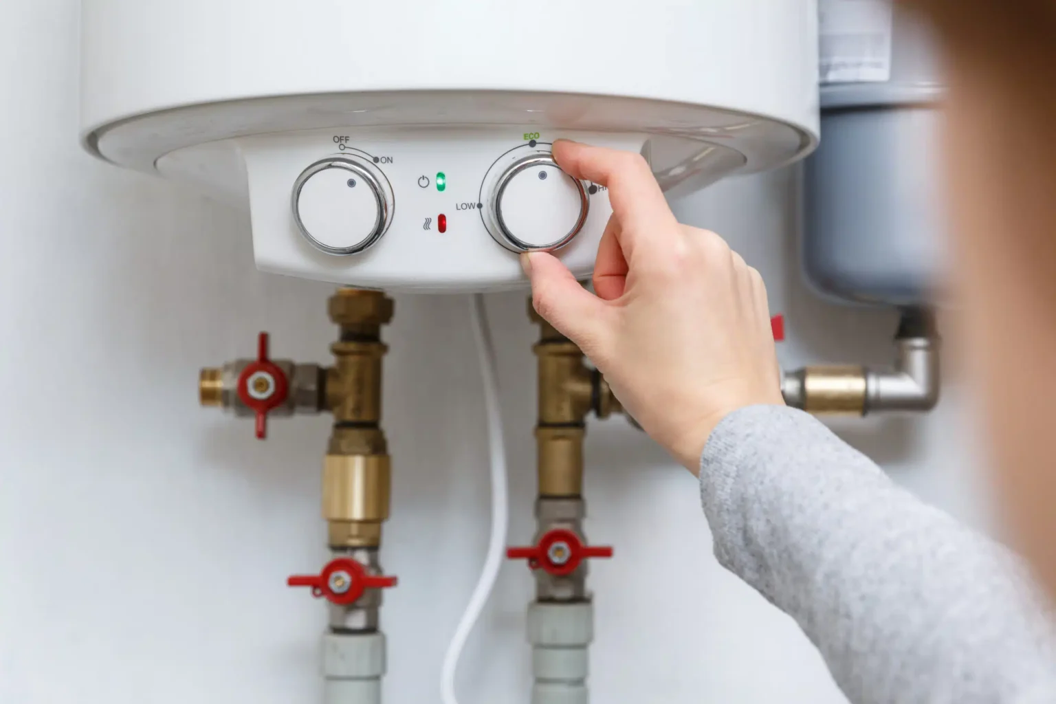 Homeowner adjusting the temperature controls on a water heater in Miami